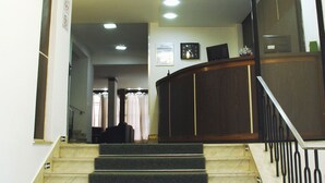 Una escalera con peldaños alfombrados que conduce a un rellano con un escritorio de madera y un televisor de pantalla plana.