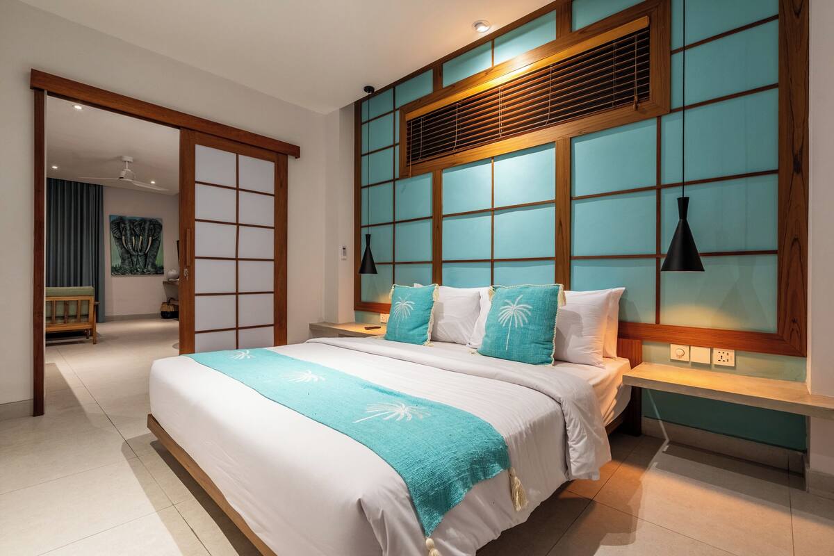 Ein modernes Schlafzimmer mit einem großen Bett, einem Holzkopfteil und einer Wand aus verschiebbaren Shoji-Schirmen.