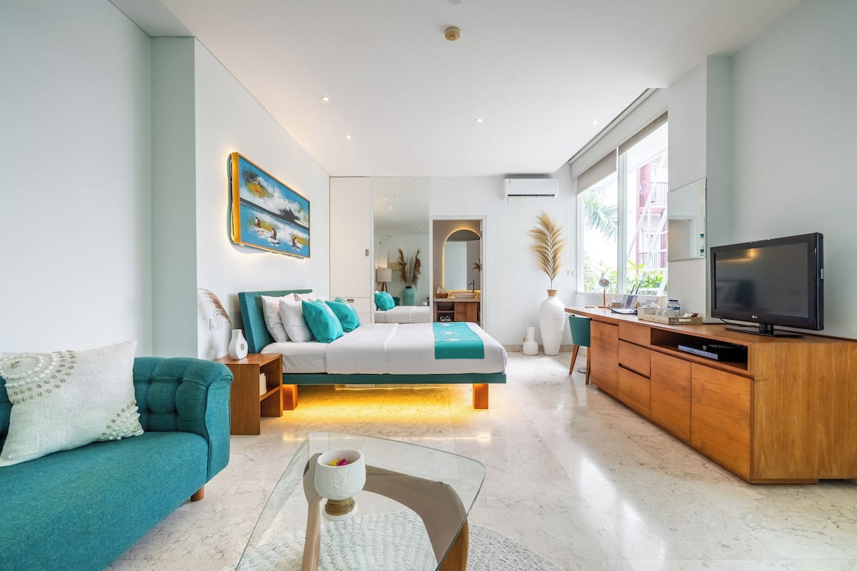 Ein modernes Schlafzimmer mit Bett, Fernseher und einer Couch.