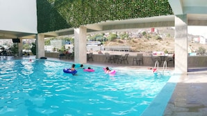 Una piscina con múltiples carriles, una zona de estar cubierta y vistas del paisaje circundante.
