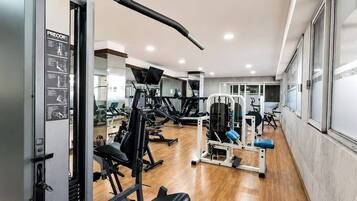 A gym with various exercise machines, a bench press, and a mirrored wall.