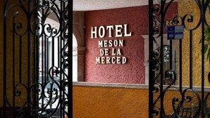Hotellin sisäänkäynti, jossa on koristeellinen takorautaportti ja kyltti, jossa lukee: »HOTEL MESON DE LA MERCED».