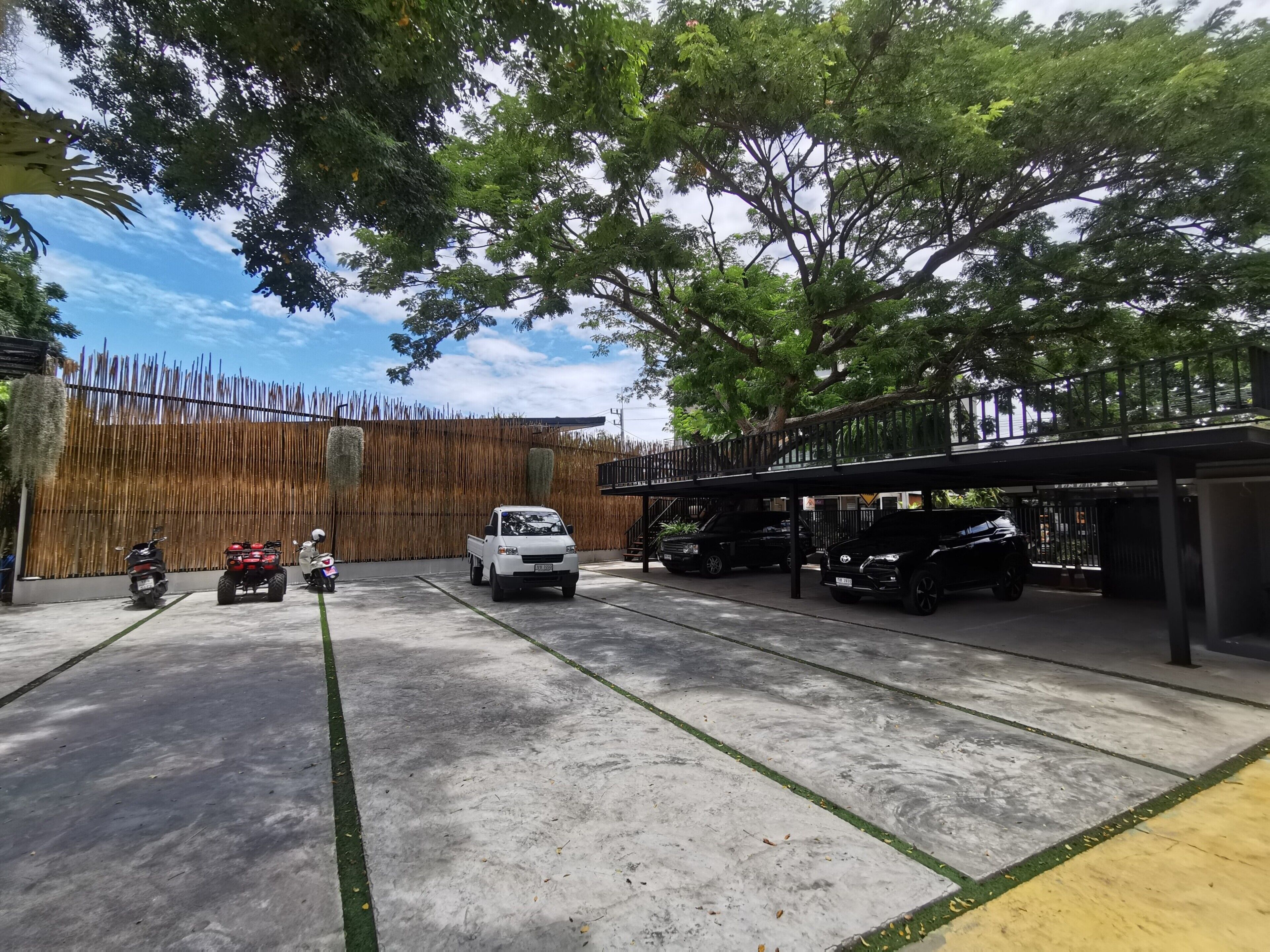 A parking area with a white pickup truck, a black SUV, and a red ATV.
