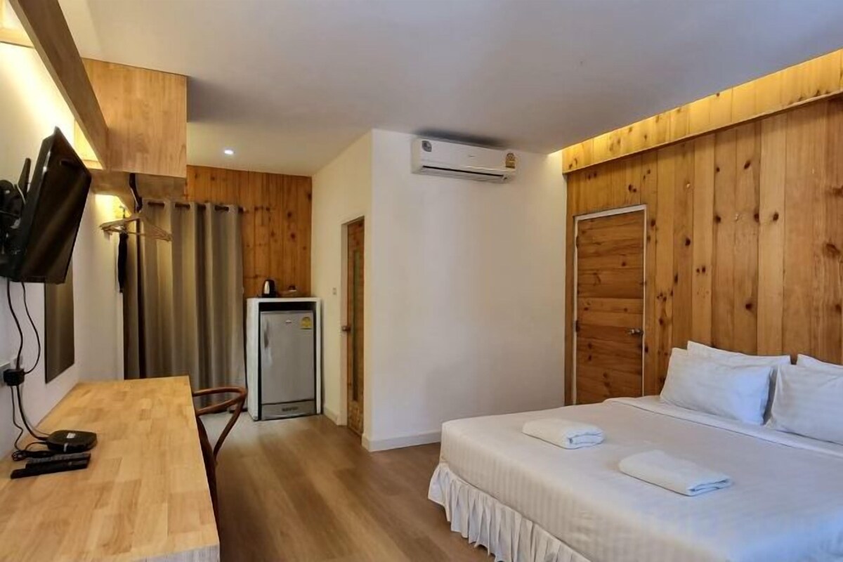 Ein Zimmer mit einem Bett, einem Schreibtisch, einem Fernseher und einer kleinen Küchenzeile.