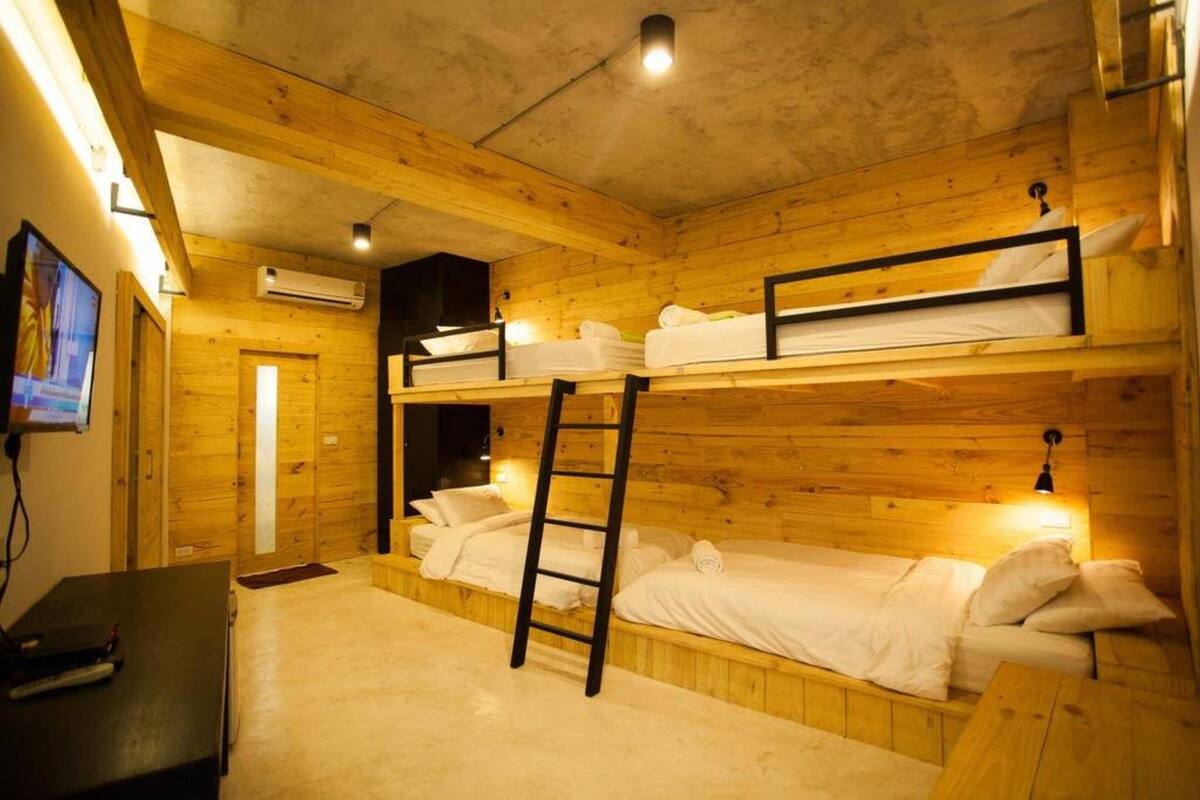 A cabin with bunk beds, a ladder, a TV, and an air conditioning unit.