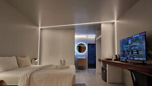 A modern hotel room with a bed, bedside lamp, desk, and television. - Amara Resort Hua Hin (Hua Hin)