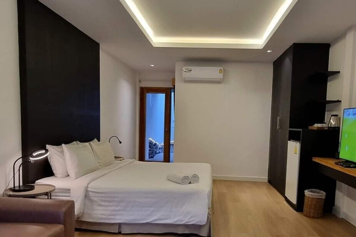 A modern hotel room with a bed, a TV, a chair, and a small table.