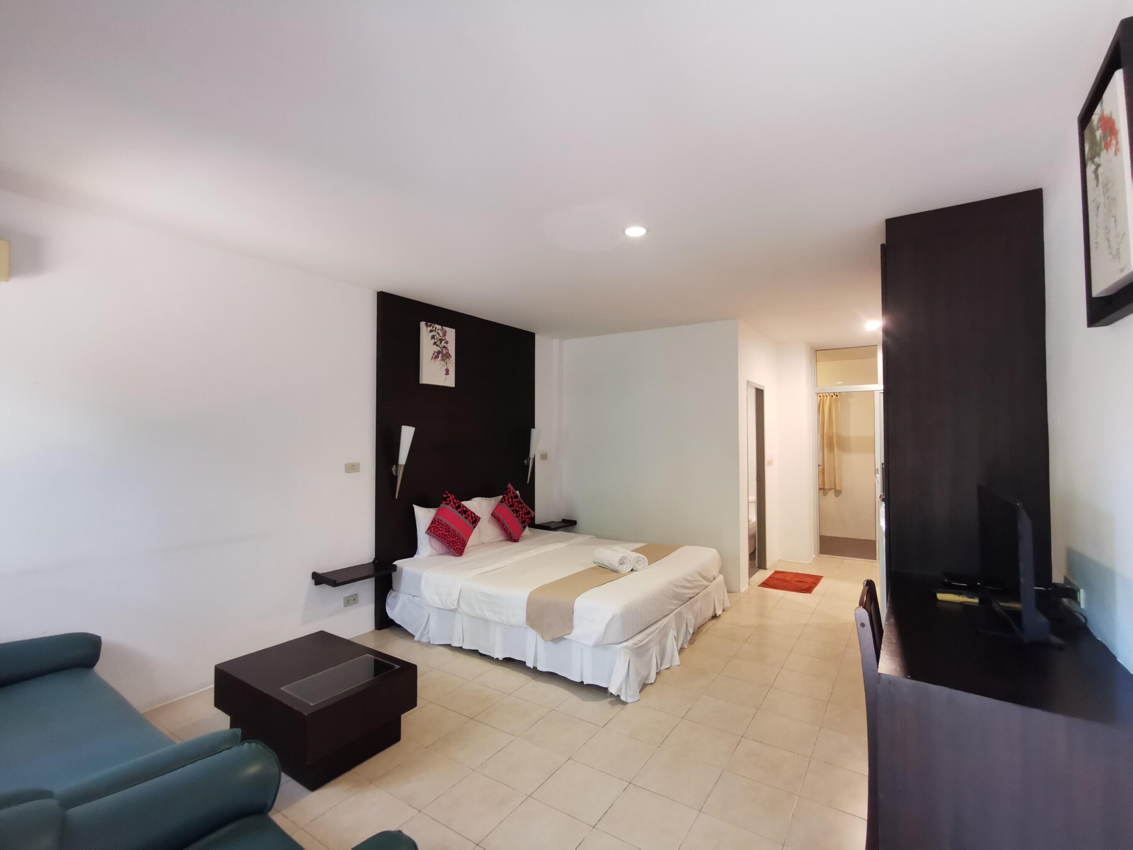 A hotel room with a bed, a small table, a sofa, and a TV.