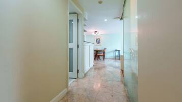 A hallway with a marble floor leading to a dining area with a table and chairs.