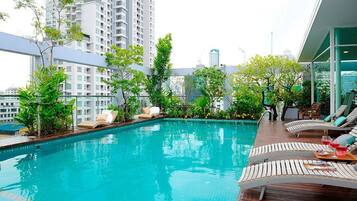 Een buitenzwembad, ligstoelen bij het zwembad