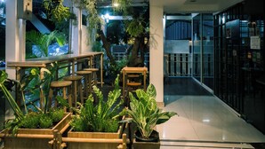 A modern indoor space with wooden planters and tables, a tiled floor, and a glass partition. - Sabai Sathorn (Bangkok)