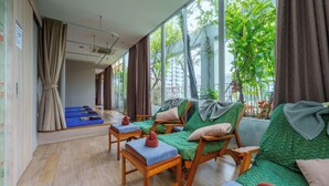 A room with a large window, wooden furniture, and a view of greenery outside. - Sabai Sathorn (Bangkok)