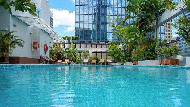 A swimming pool with lounge chairs, a lifebuoy, and a modern building in the background. - Sabai Sathorn (Bangkok)