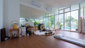 A spacious room with large windows, a wooden floor, and a variety of decorative items including bowls and a drum. - Sabai Sathorn (Bangkok)