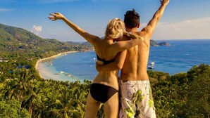 A couple embracing with a scenic view of a beach and ocean. - Monkey Flower Villas (Koh Tao)