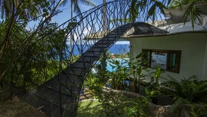 A staircase leading to a house with a view of the ocean, surrounded by lush greenery. - Monkey Flower Villas (Koh Tao)