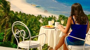 A woman dining at a table with a view of a beach and ocean. - Monkey Flower Villas (Koh Tao)