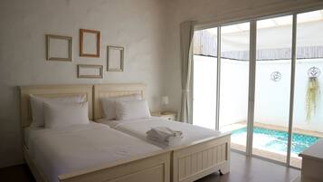 A bedroom with two beds, a view of a swimming pool, and a sliding glass door to the outdoors.