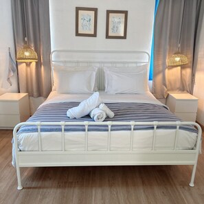 A bed with white bedding, two framed pictures on the wall, and two bedside lamps.