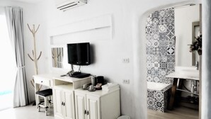 A modern room with a white cabinet, a mounted TV, an air conditioner, and a patterned tile backsplash. - Costa Village Pool Villa (Pattaya)