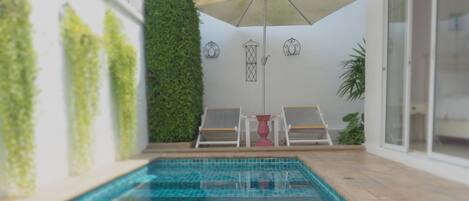 A swimming pool with tiled flooring, a ceiling fan, and a potted plant.