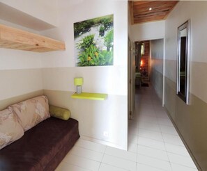 A hallway with a wooden ceiling, a brown sofa, a yellow shelf, and a framed picture on the wall. - L'Orky-Mel (Petite-Ile)