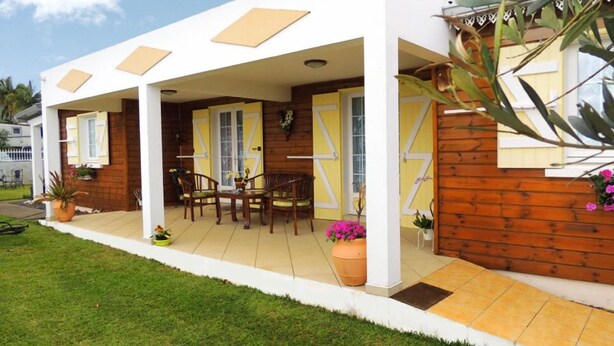 A modern house with a covered patio, wooden exterior, and a small garden area. - L'Orky-Mel (Petite-Ile)