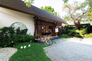 A modern building with a covered entrance, a bicycle parked outside, and a well-maintained garden.