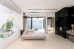 A modern bedroom with a large bed, a view of the sea, and a sliding glass door leading to a balcony.