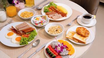 A breakfast table with plates of food, a cup of coffee, and a glass of orange juice.
