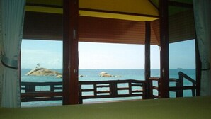 Quarto com vista para o mar, com varanda de madeira e teto amarelo.