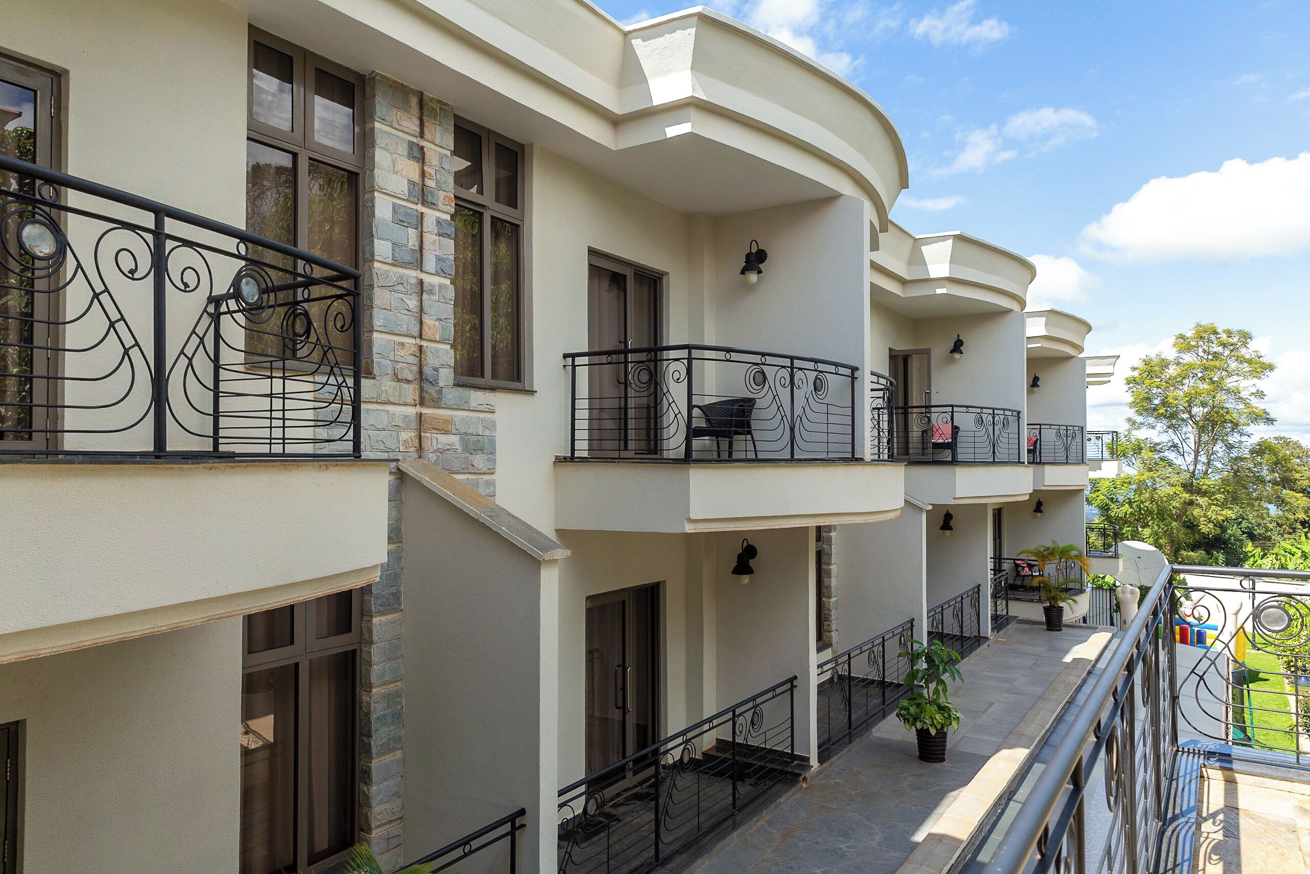 A multi-story building with balconies, stone accents, and outdoor seating areas.