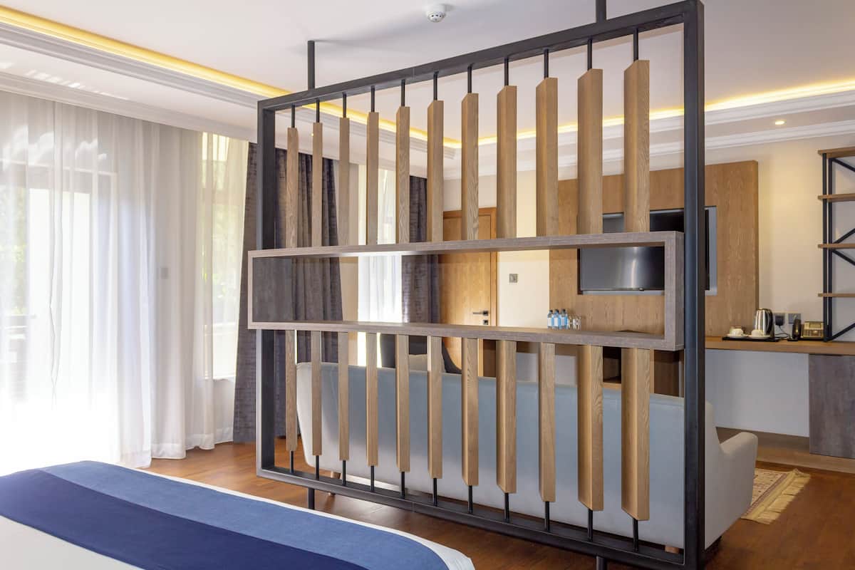 A hotel room with a bed, a desk, a kitchenette, and a view of the outdoors.