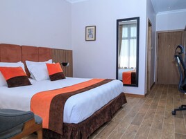 Una habitación de hotel con una cama, una silla, un espejo y una puerta.