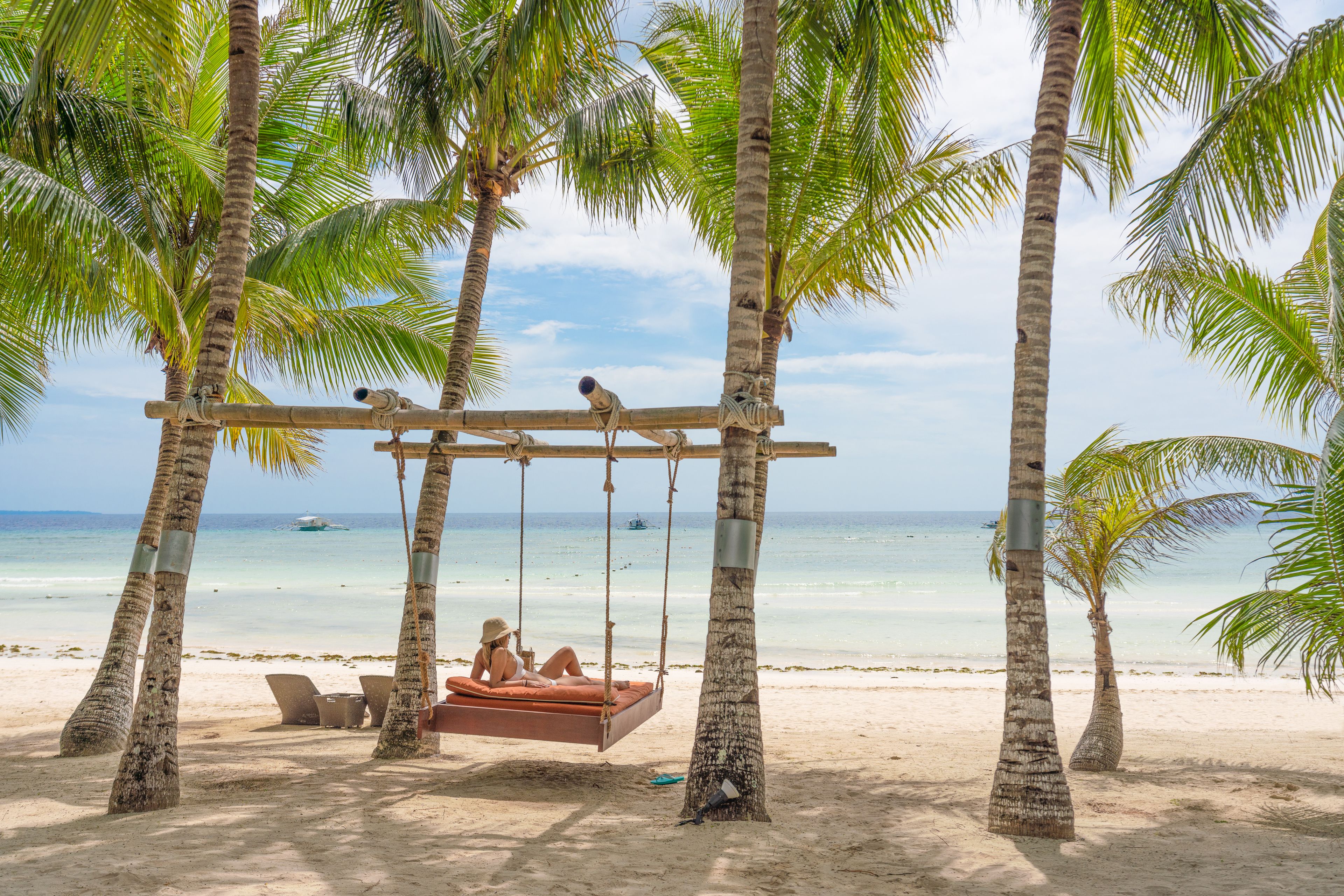 Escena de playa con un columpio, palmeras y una vista despejada del océano.