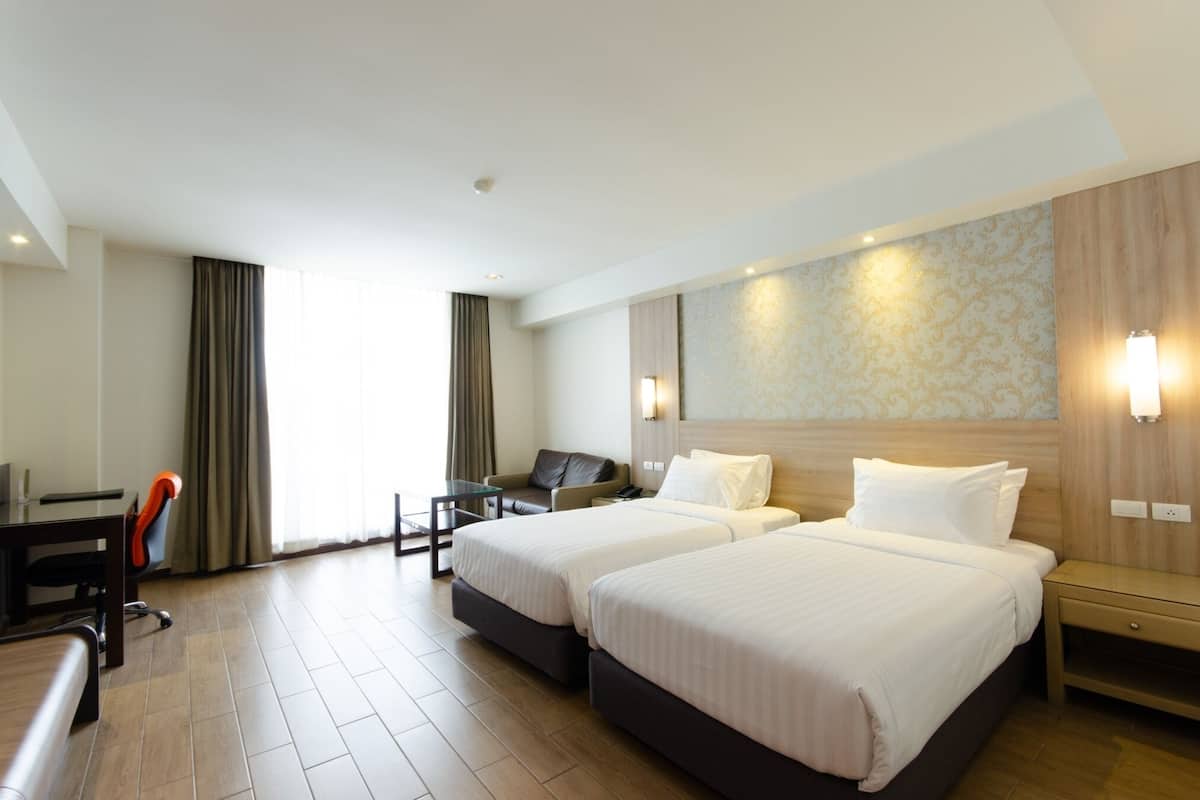 A hotel room with two beds, a desk, and a chair.