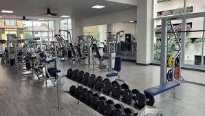 A gym with various exercise machines, weight racks, and benches. - Dynasty Grande Hotel (Bangkok)