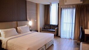 A hotel room with a large bed, a desk, a chair, and a sofa. - Marsi Hotel (Bangkok)