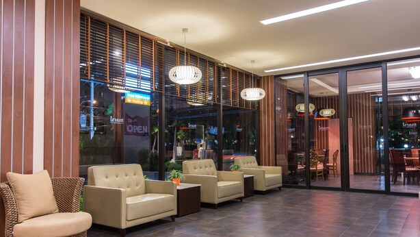 A lobby with a seating area, a reception desk, and a view of the street outside. - Marsi Hotel (Bangkok)