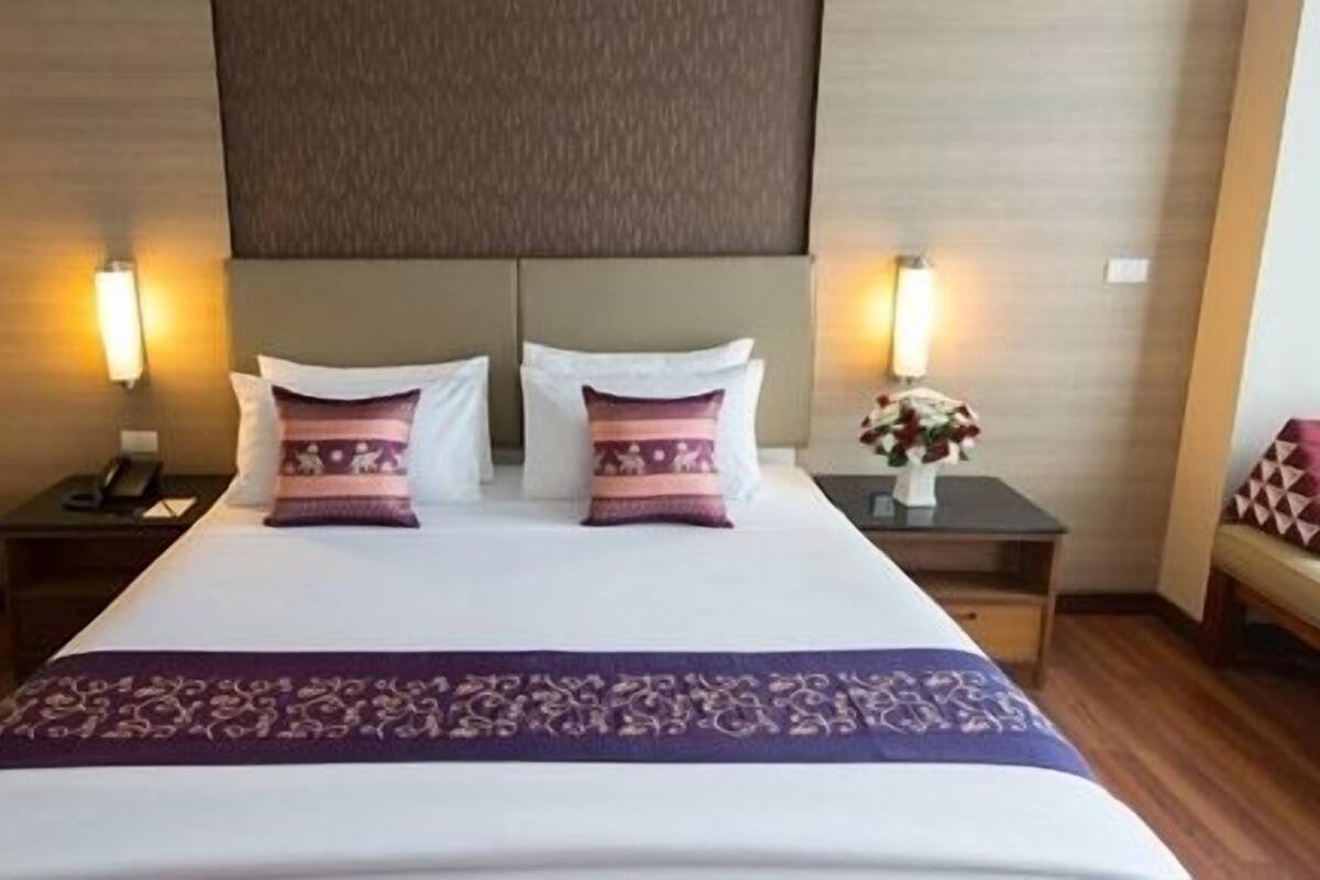 A hotel room with a large bed, two bedside tables, and a nightstand.