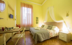 Una habitación con cama, mesita de noche y un escritorio con silla.