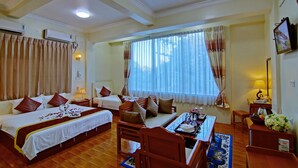 A hotel room with a large bed, a sofa, a dining table, and a window with curtains. - 79 Living Hotel (Mandalay)