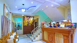 A reception area with a wooden desk, a staircase, and a reception sign. - 79 Living Hotel (Mandalay)