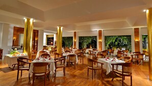 A spacious dining area with multiple tables and chairs, wooden flooring, and a backdrop of greenery. - Areindmar Hotel (Nyaung-U)
