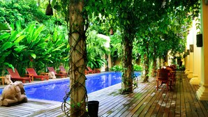 A pool area with wooden deck, lounge chairs, and a statue. - Areindmar Hotel (Nyaung-U)