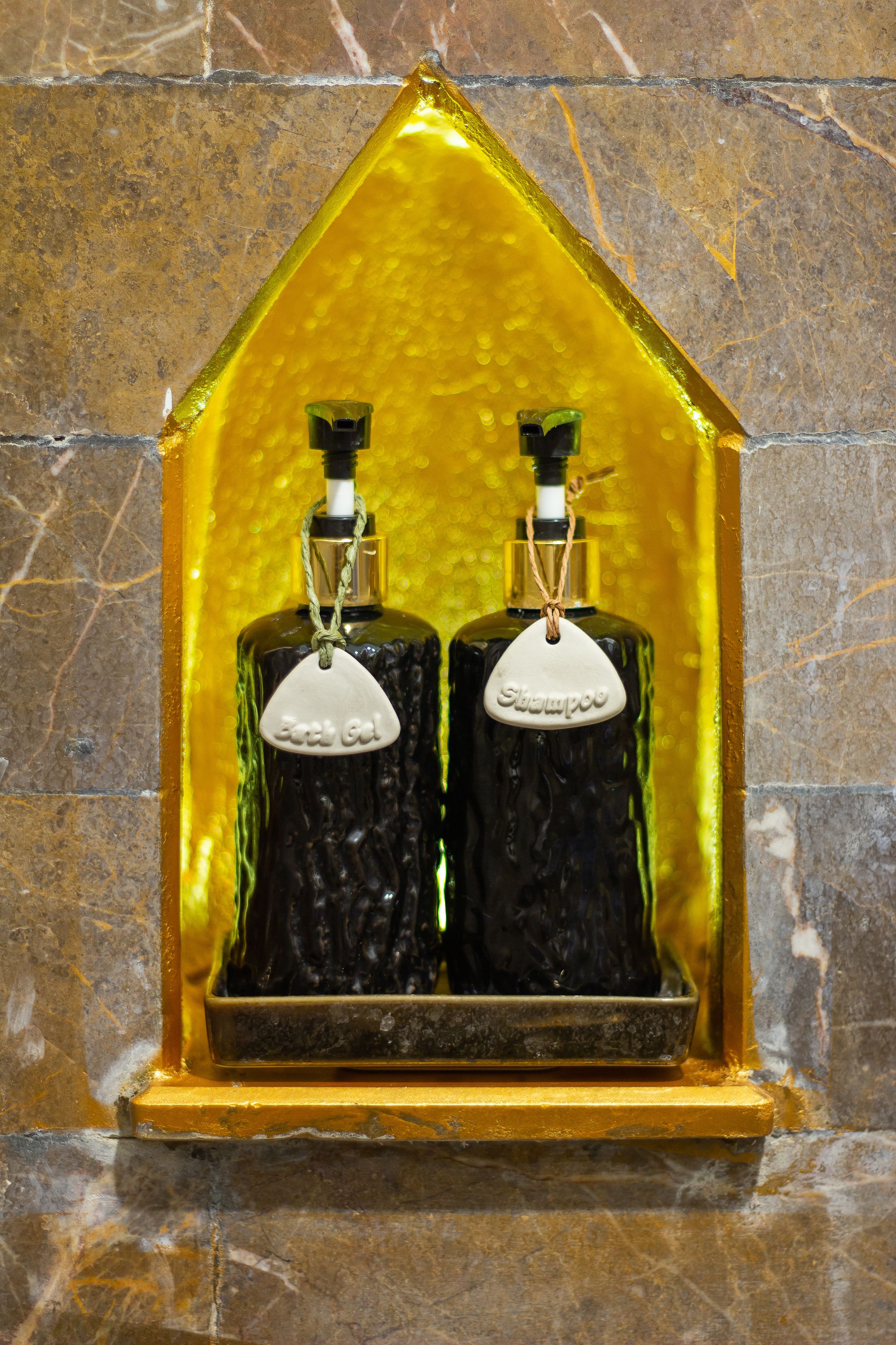 Two bottles of shampoo in a glass display case with a yellow background.