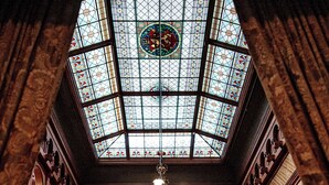 A grand hall with a large stained glass ceiling, wooden paneling, and a chandelier. - Dalen Hotel (Tokke)
