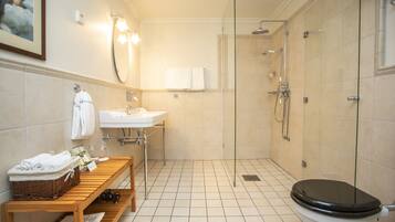 Une salle de bain moderne avec une douche à parois de verre, un banc en bois, un lavabo et des toilettes.