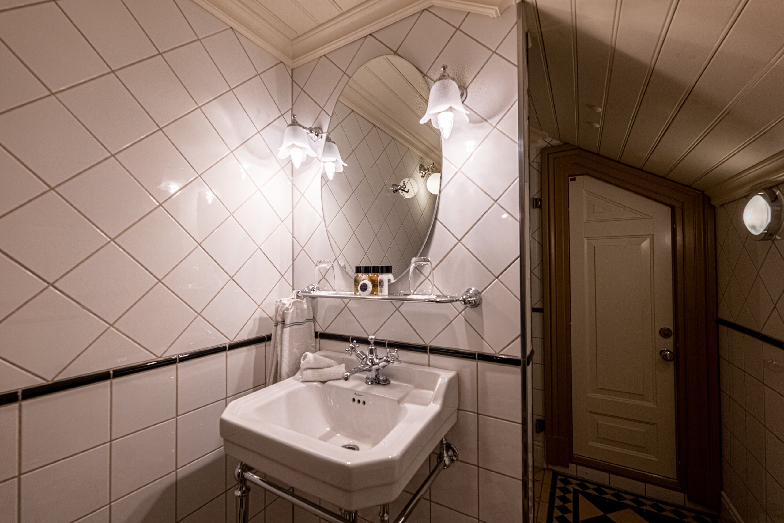 A bathroom with a white sink, mirror, and light fixtures.