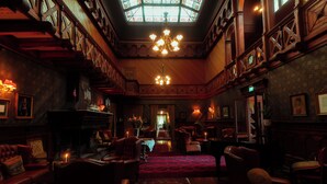 A grand room with a chandelier, wooden paneling, and a red carpet. - Dalen Hotel (Tokke)